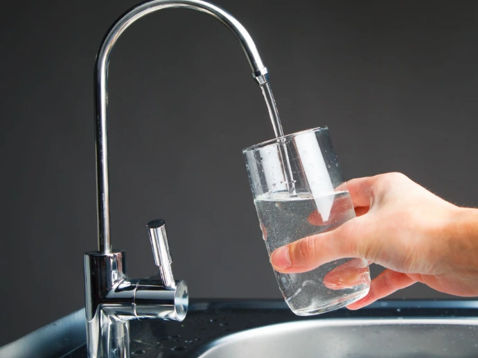 hand filling glass with filtered water to drink